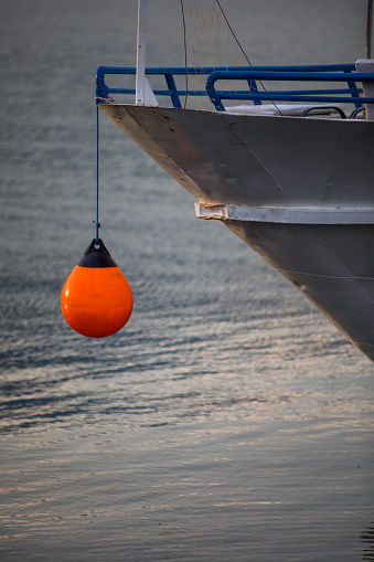 Orange mooring buoy hanging from a ship