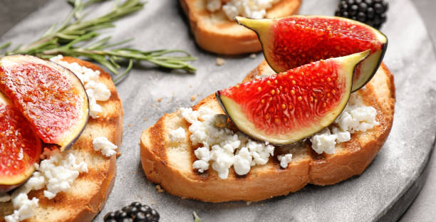 istock Bruschettas with figs and cheese served on board, closeup. Banner design 1358635414