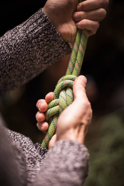 Detail with a climber's hands tying a figure eight know to the harness.