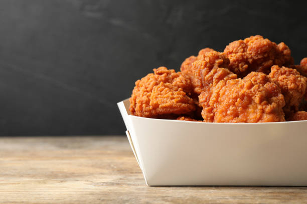 istock Tasty deep fried chicken pieces on wooden table, closeup. Space for text 1358635571