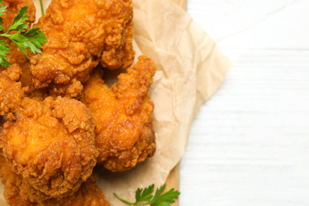 istock Tasty deep fried chicken pieces on white wooden table, top view. Space for text 1358636555