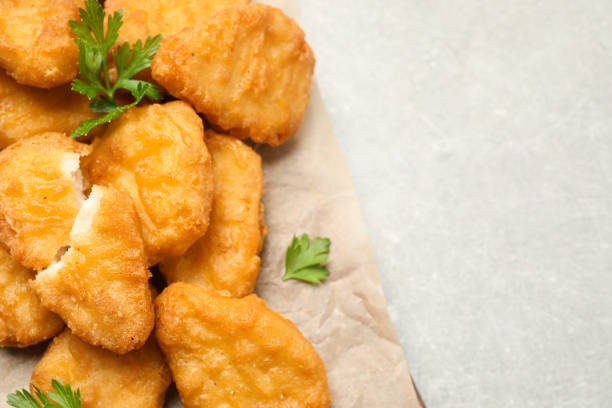 istock Tasty fried chicken nuggets on light grey table, top view. Space for text 1358637451