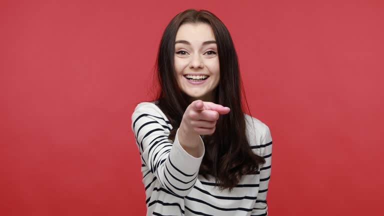 Woman pointing fingers on you looking at camera with toothy smile, congratulating with victory.