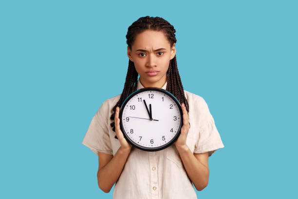 istock Woman with dreadlocks holding big wall clock, looking at camera with unpleasant emotions, time to go 1358638904