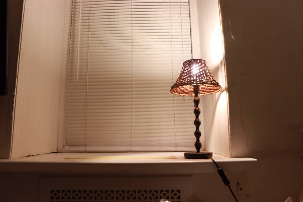 istock night lamp on a white windowsill against a background of blinds, conceptual Reflection 1358638960