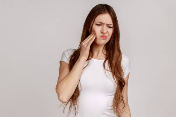 Sick woman touching cheek with expression of terrible suffer from toothache, sensitive teeth. stock photo