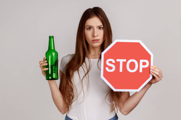 アルコール飲料ビール瓶と停止サイン、警告と心配を示す不安な美しい女性。 - eastern european caucasian one person alcoholism ストックフォトと画像