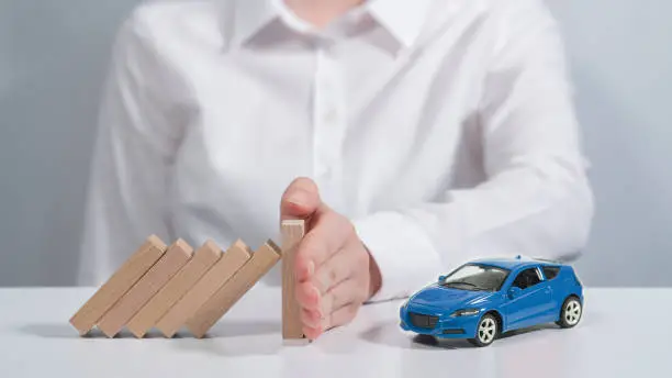 Photo of Next to the little blue car is a person's hand that prevents dangers from coming to her.