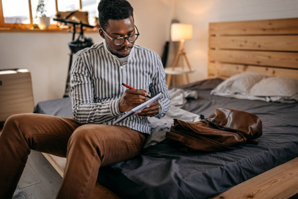 istock Men writing in book at home in room 1358643749