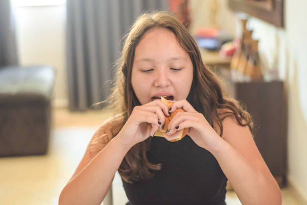 istock Young girl at home, eating bread 1358643788