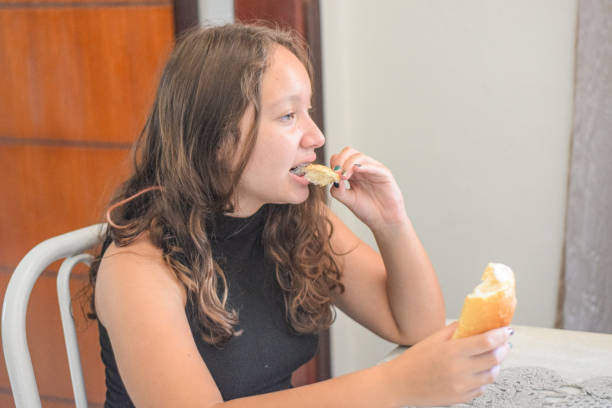 Young girl at home, eating bread