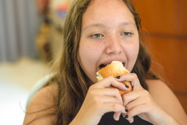 istock Young girl at home, eating bread 1358644460