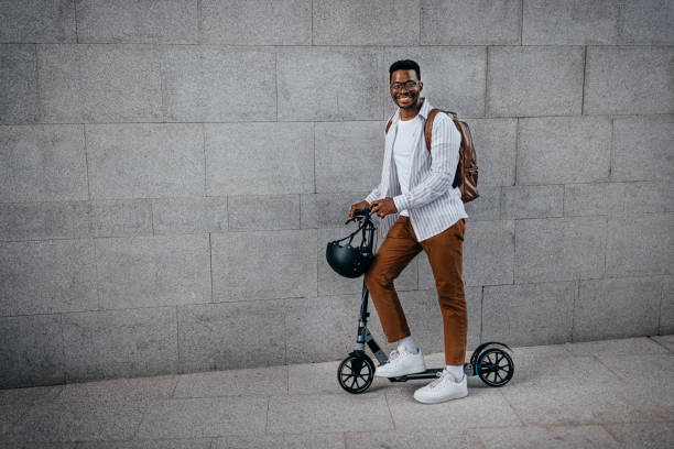 istock Man with push scooter standing holding helmet 1358647112
