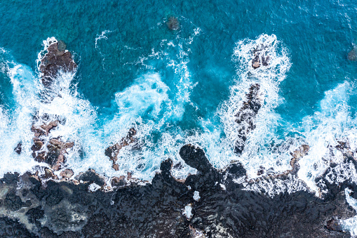Waves crashing into black volcanic rock in Big Island, Hawaii