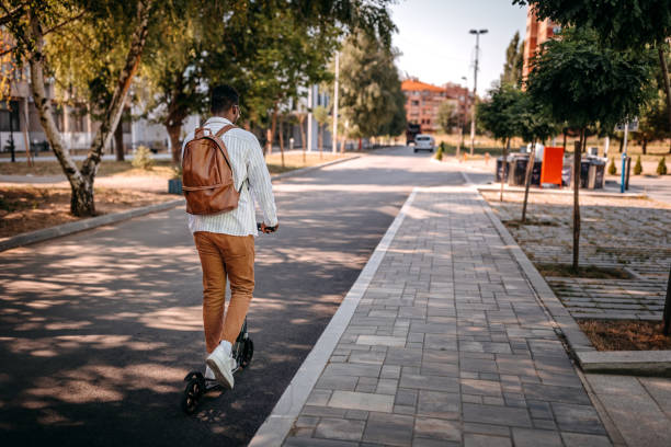 istock Man riding push scooter in street 1358647177