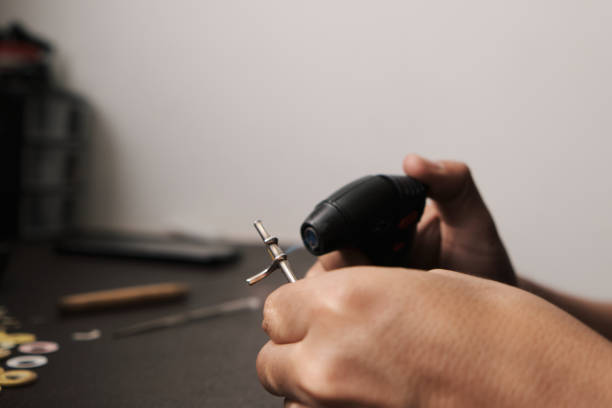 les mains d’un homme appliquant une flamme sur les touches d’une flûte dans son atelier de réparation d’instruments - flute musical instrument music key photos et images de collection