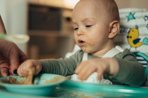 istock Adorable little baby eating his dinner and making a mess 1358654179