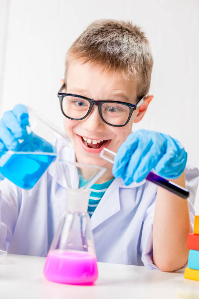 istock A schoolboy studies multi-colored substances in test tubes, conducts experiments - a portrait on a white background. Concept for the study of coronavirus in the laboratory 1358655339
