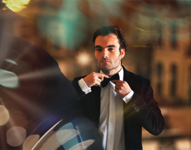 man preparing bow tie and tuxedo for function stock photo