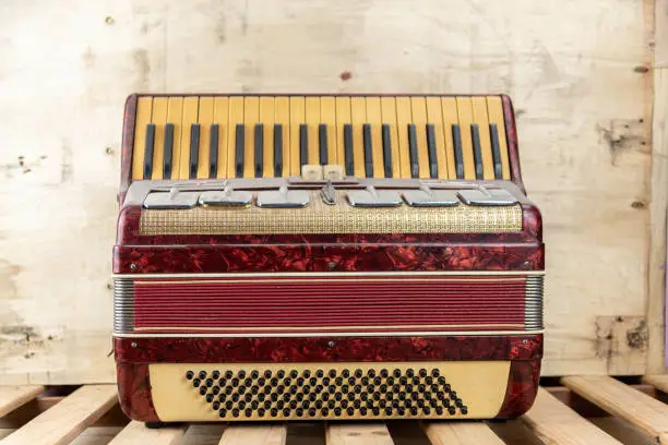 Old red accordion covered with dust. Also popularly called accordion and harmonica, it is an aerophone musical instrument of German origin.
