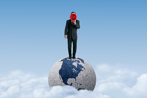 A businessman standing on top of a globe that emerges from the clouds and is rotated to show North America shouts through a red megaphone. The file was created using Adobe Photoshop. Map source: https://svs.gsfc.nasa.gov/vis/a000000/a003400/a003484/aim_seasonb_GEOmove.HRstills.0000.jpg