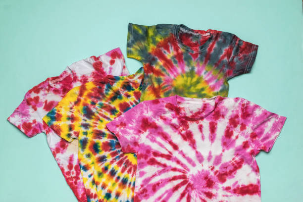 istock Several tie dye-style T-shirts on a blue background. Flat lay. 1358669937