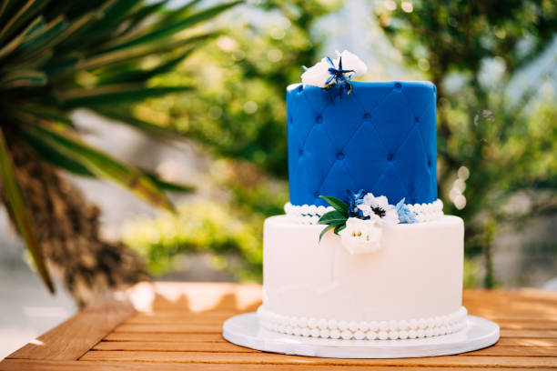 白と青のウェディングケーキとビーズと花が木製のテーブルの上に立っています - flower cake cookie food ストックフォトと画像