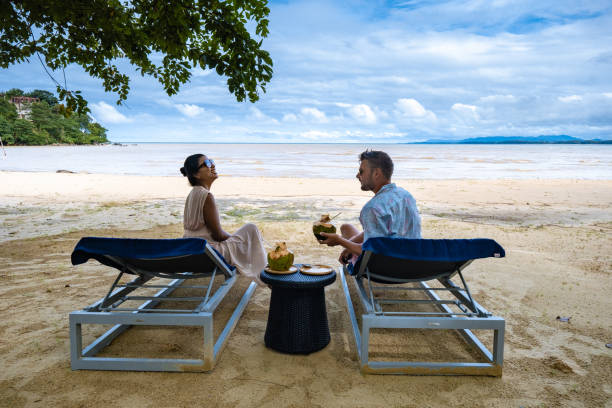 couple man and woman on the beach in Phuket Thailand, Nai Yang beach with hidden Island in front stock photo