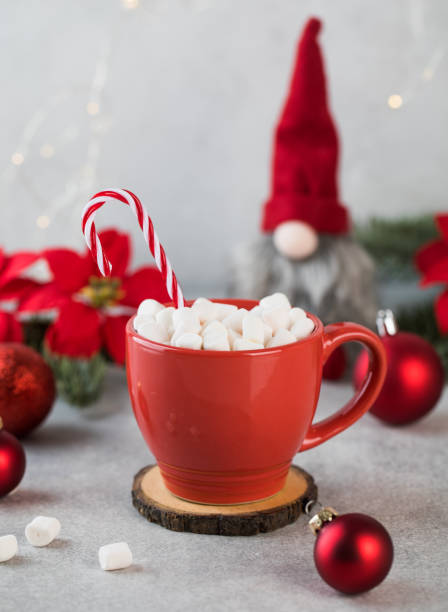 istock New Year card. Red cocoa mug with marshmallows, striped candy and Christmas tree decorations. 1358676184