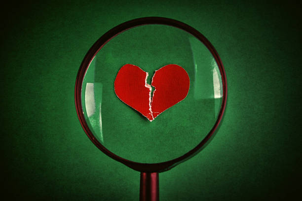Broken Heart Shape in the Magnifying Glass on the Green Paper Background