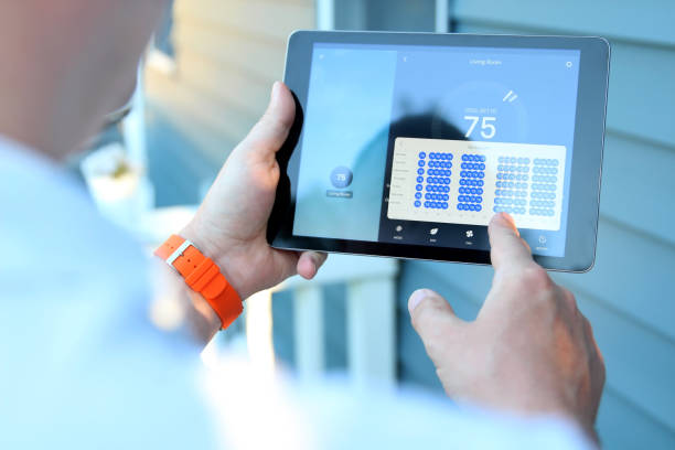 mann passt eine temperatur mit einem tablet mit smart-home-app an - heating plant stock-fotos und bilder