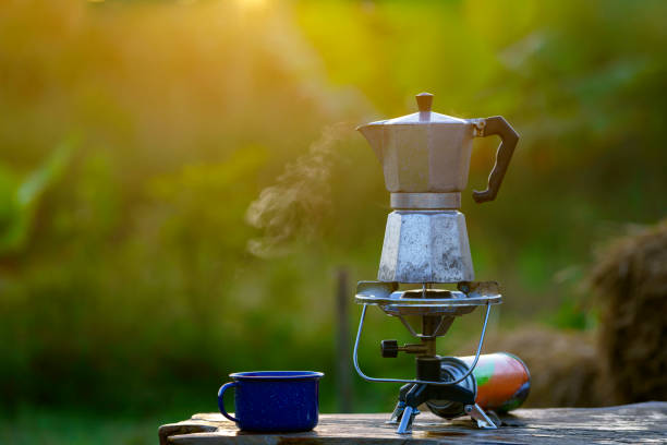 アンティークコーヒーポット 朝に太陽が昇るときにキャンプのためのガスストーブの上に。 - cooking kitchen utensil wood isolated ストックフォトと画像