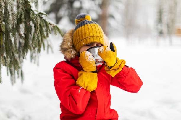 istock Little boy drinking tea in winter forest 1358700901