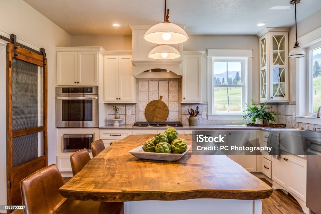 Country kitchen with apron sink in Montana Natural wood countertop on island with dome pendant lights above Kitchen Stock Photo