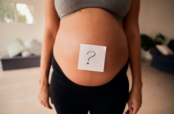 torso de una hembra embarazada caucásica de pie con signo de interrogación en el vientre. revelación de género, estilo de vida moderno - ewan fotografías e imágenes de stock