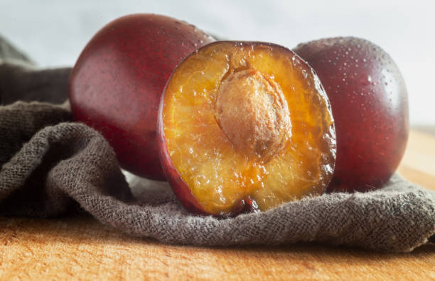 istock Two ripe plums and half a cut plum with a stone 1358707515