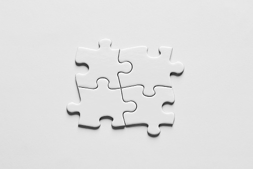 Four puzzle pieces connected to each other. Teamwork, synergy, connection, cooperation, unity or togetherness concept.