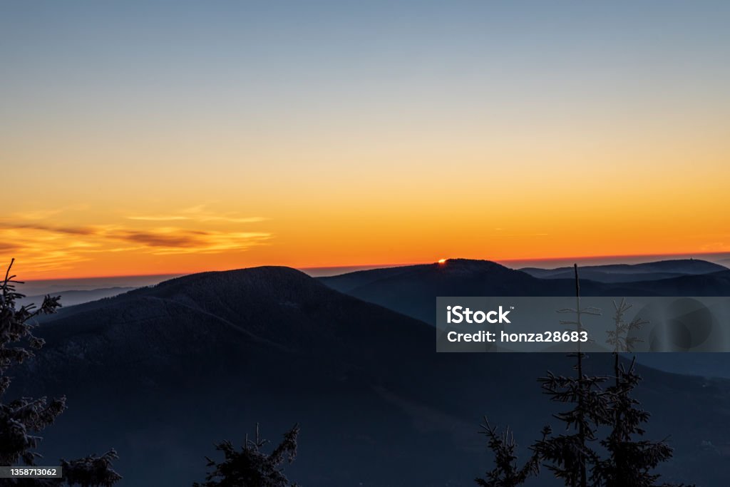 Sunset from Lysa hora hill in Moravskoslezske Beskydy mountains in Czech republic Sunset with orange sky and few clouds from Lysa hora hill in Moravskoslezske Beskydy mountains in Czech republic Autumn Stock Photo