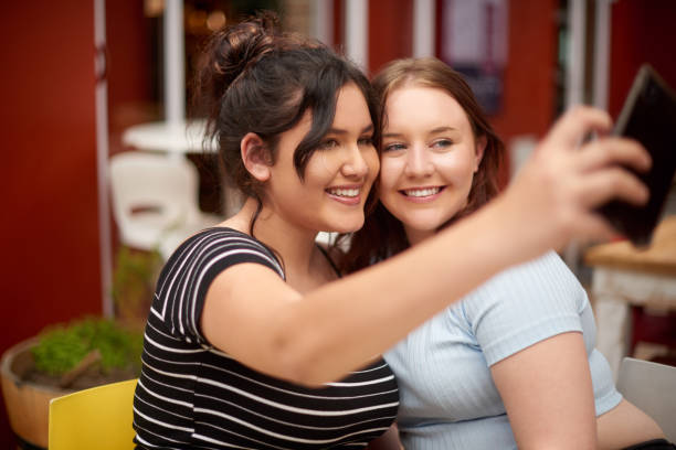 istock Shot of two friends taking selfies together while at a restaurant 1358713414