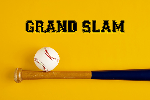 Baseball bat and a ball on yellow background with the word grand slam. Baseball terms concept.