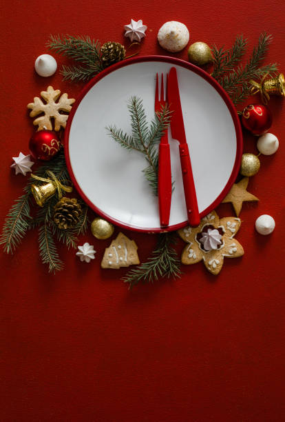 istock Christmas and New year setting table. White empty plate with cutlery and Christmas tree branches, red napkin on a red concrete background. 1358719824