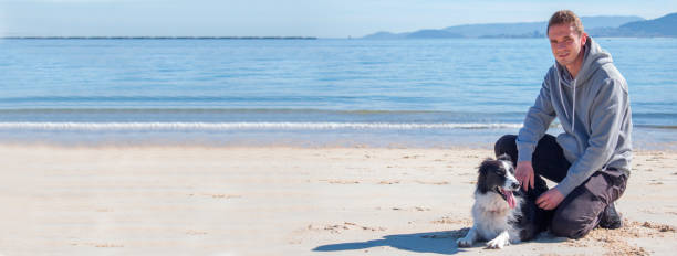 istock smiling man sitting on the beach with his dog 1358720028