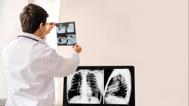 istock Back view of young man radiologist doctor holding and analysis x-ray and computed tomography film in his xray room from a hospital. 1358724704