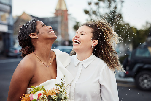 Shot of a young lesbian couple standing outside together and celebrating their wedding