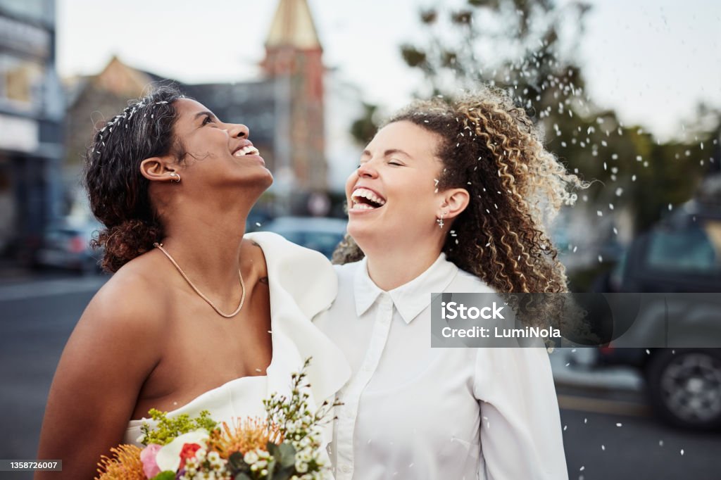 Shot of a young lesbian couple standing outside together and celebrating their wedding Love conquers all Wedding Stock Photo