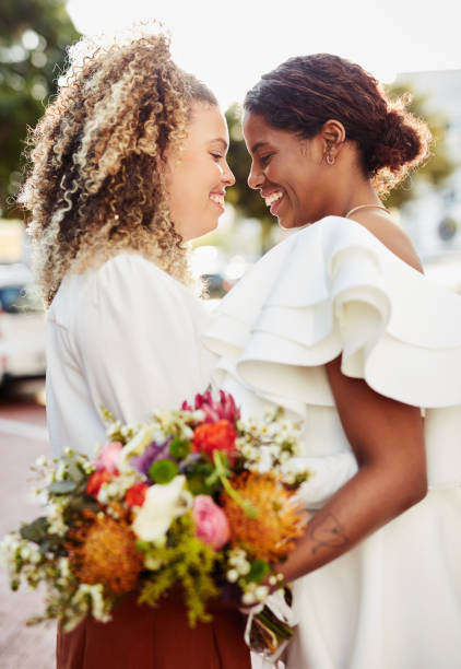 Shot of a young lesbian couple standing outside together and sharing a romantic moment after their wedding stock photo