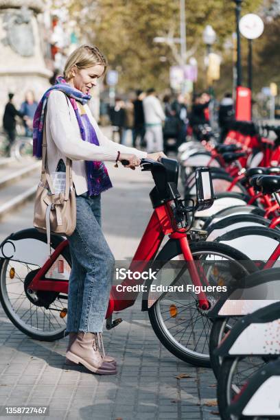 Tourist Woman Taking A Red Bicycle In A Bike Rental Station In The City Stock Photo - Download Image Now