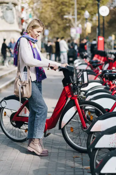 Tourist Woman taking a red bicycle in a bike rental station in the city