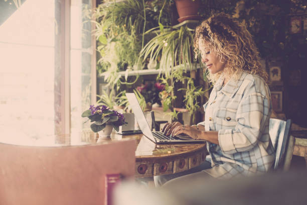 istock Side View Of Woman Using Laptop At Cafe 1358728295