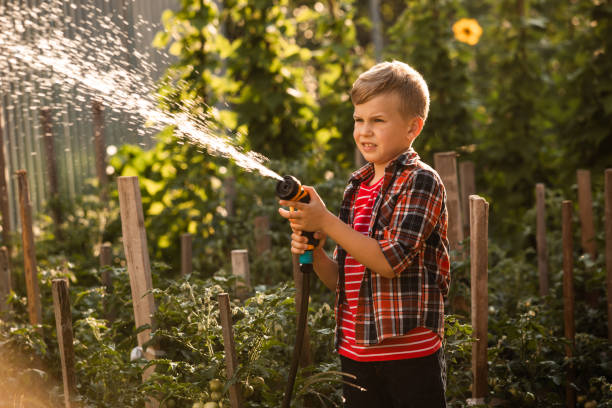 istock Boy Holding Umbrella Standing Against Plants 1358728718